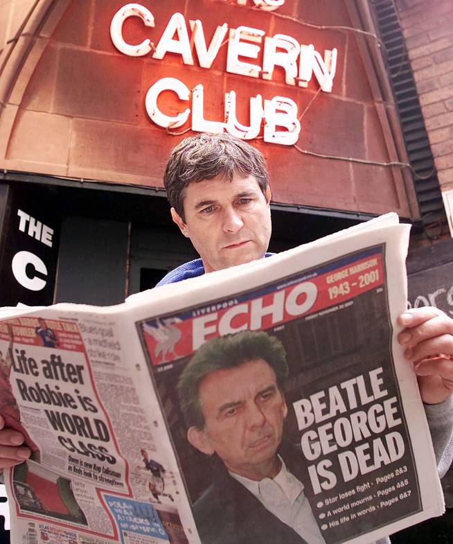 A citizen of Liverpool reads in the newspaper about the death of Beatle George Harrison outside the famous venue The Cavern Club.