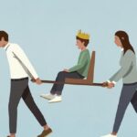 Parents carrying son with crown in chair